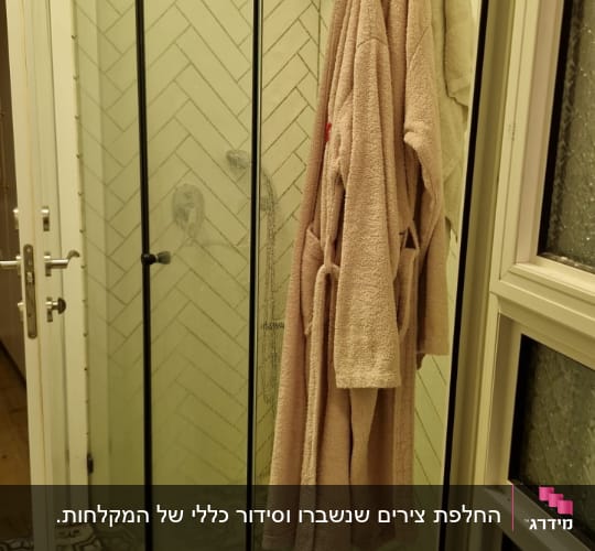 מקלחון זכוכית עם חלוק תלוי על וו